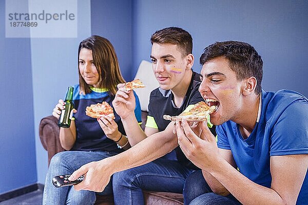 Fußballfans auf der Couch essen Pizza