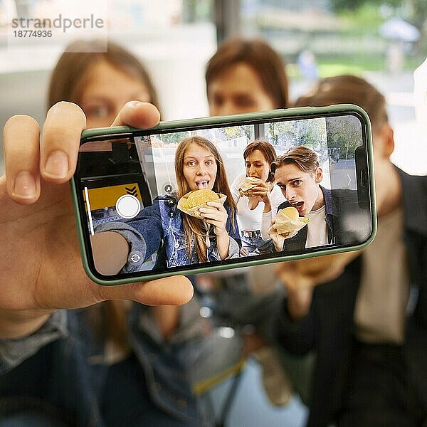 Gruppe von Freunden  die gemeinsam ein Selfie machen  während sie Fast Food essen