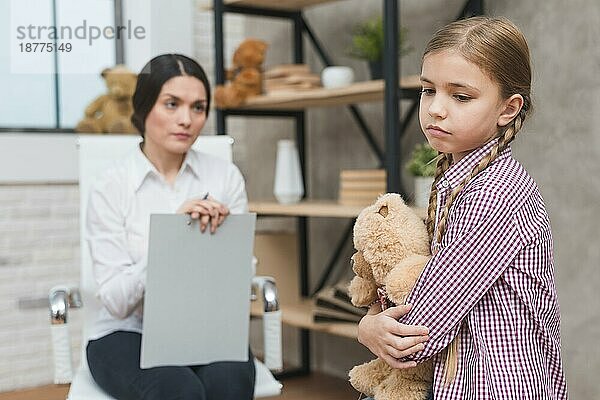 Close up weiblichen Psychologen suchen traurig Mädchen hält Teddybär