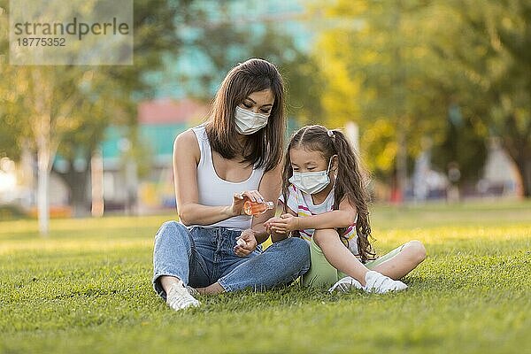 Asiatische Mutter Tochter verwendet Desinfektionsmittel im Freien