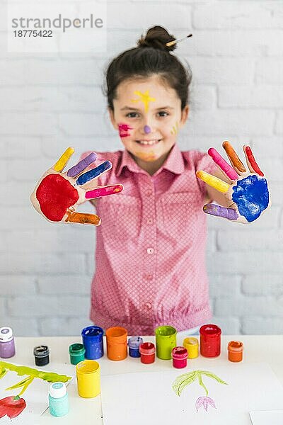 Lächelndes Portrait-Mädchen zeigt ihre bemalte bunte Hand