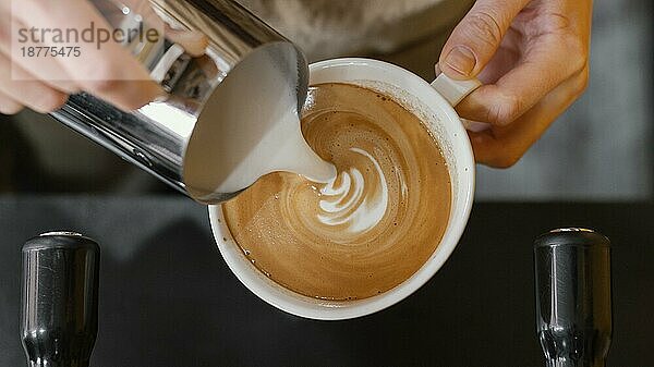 Draufsicht männlicher Barista  der Milch in Kaffeetassen gießt Foto mit hoher Auflösung
