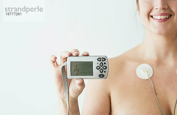 Frau mit Elektroden hält Monitor mit Kardiogramm. Foto mit hoher Auflösung