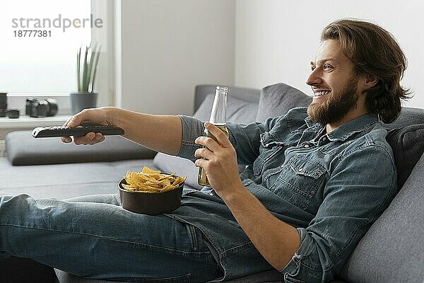 Medium shot Mann mit Getränk vor dem Fernseher