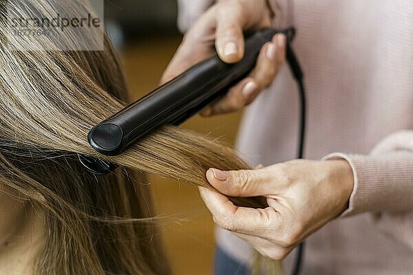 Frau  die sich zu Hause die Haare glättet. Auflösung und hohe Qualität schönes Foto