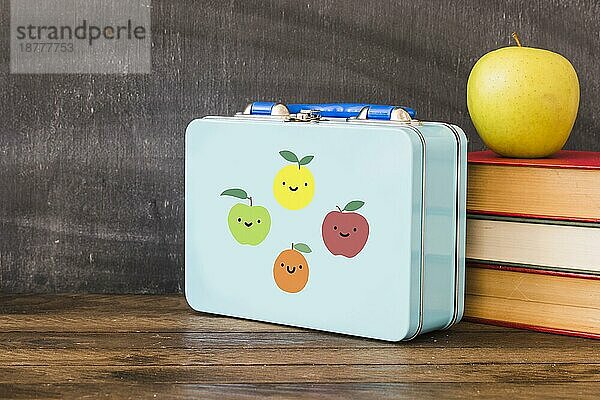 Lunchbox in der Nähe von Stapel Bücher Apfel