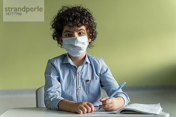 Vorderansicht Junge mit medizinischer Maske Schule während Pandemie. Schönes Foto