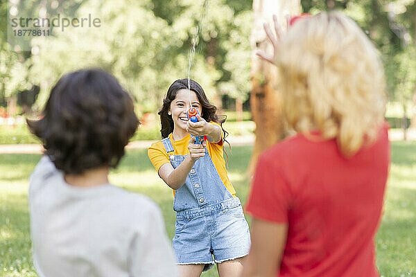 Kinder spielen im Park mit einer Wasserpistole