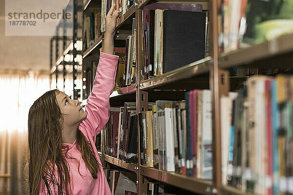 Mädchen wählt ein Buch aus dem Bücherregal aus