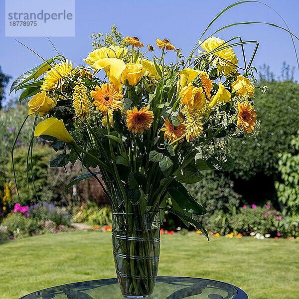 Gelbe Blumen in einer Vase auf einem Gartentisch
