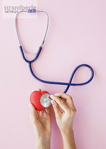 Draufsicht Hände  die das Herz mit einem Stethoskop prüfen