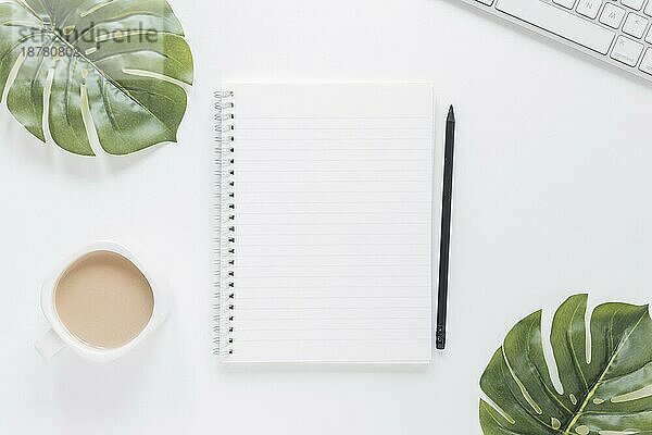 Notebook in der Nähe von Kaffeetasse Tastatur Tisch mit grünen Blättern . Auflösung und hohe Qualität schönes Foto