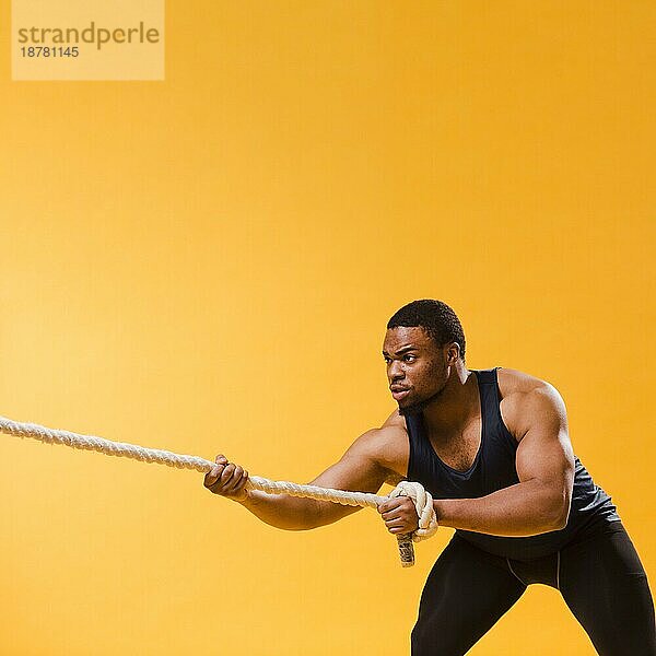 Athletischer Mann in Fitnessstudio-Outfit  der ein Seil zieht  mit Kopiervorlage