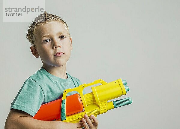 Niedliches Kind spielt mit Wasserpistole