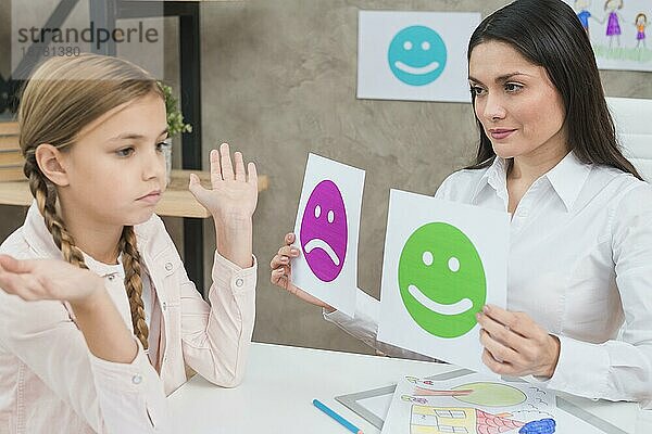Lächelnd Psychologe zeigt glücklich traurig Emotion Gesichter Karten Mädchen Kind. Hohe Auflösung Foto