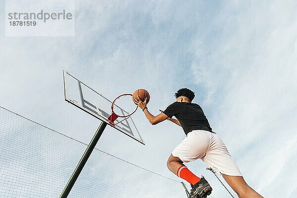 Cooler sportlicher Mann wirft Basketball in den Korb. Foto mit hoher Auflösung