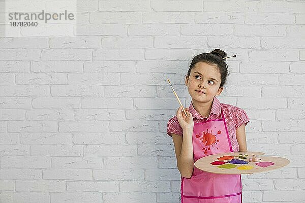 Porträt Mädchen mit Pinsel Palette stehen gegen weiße Wand