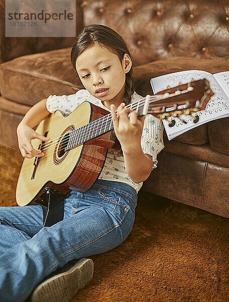Mädchen lernt  wie man zu Hause Gitarre spielt
