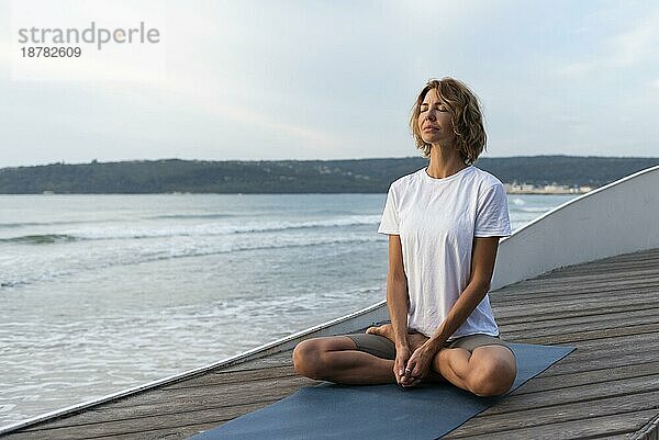 Frau übt Yoga-Pose am Meer