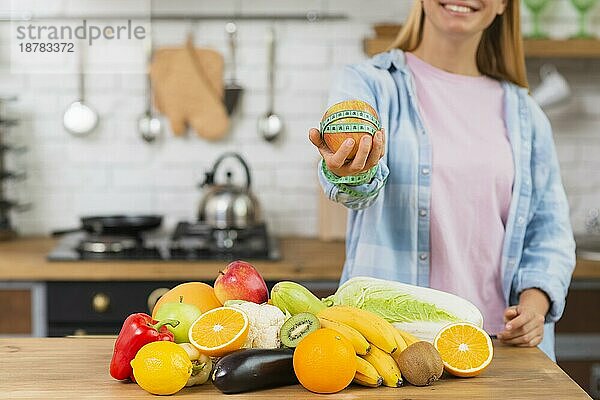 Nahaufnahme eines lächelnden Mädchens  das einen Apfel hochhält