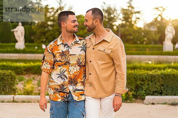 Romantisches Porträt von Homosexuell Jungvermählten zu Fuß und mit Spaß bei Sonnenuntergang in einem Park in der Stadt. Vielfalt und lgbt Konzept