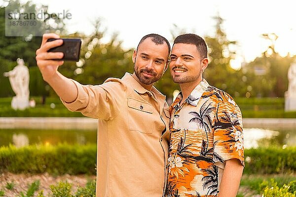 Homosexuelles Paar macht ein Selfie bei Sonnenuntergang in einem Park in der Stadt. Vielfalt und lgbt Konzept