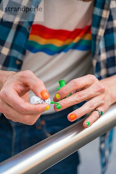 Attraktive Homosexuell Mann malt seine Nägel Make up mit Regenbogen lgbt Flagge in der Stadt  Stolz Partei und homosexuell