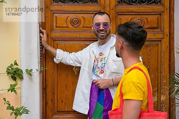 Lgbt Konzept  schwules männliches Paar schüttelt Freunde  um zur Pride Party mit Regenbogenfahne zu gehen