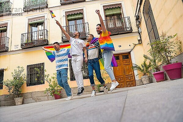 Homosexuelle männliche Freunde springen vor Freude bei der Gay Pride Party  Vielfalt der jungen Menschen in der Stadt  Straße zur Demonstration mit den Regenbogenfahnen  lgbt Konzept