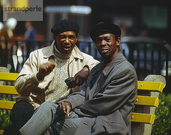 2 zwei junge Afrikaner sitzen auf einer auf einer Bank und reden miteinander