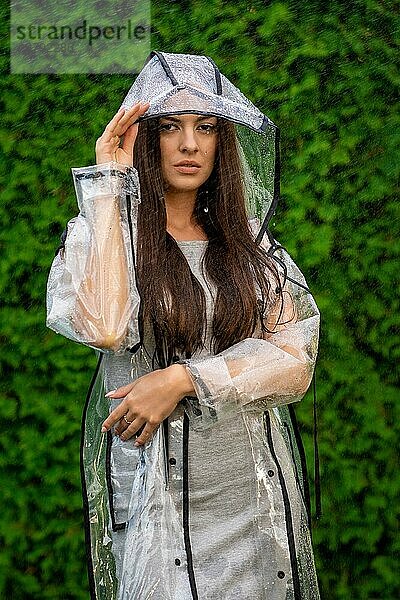 Junge schöne Frau in Regenmantel mit Kapuze an einem regnerischen Tag