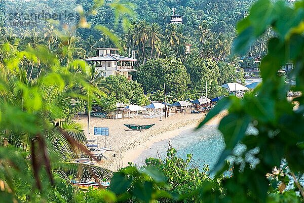 Am Strand eines der wichtigsten Touristenzentren im Süden Sri Lankas. Früher Morgen in Unawatuna. Ausleger Sport und Fischerboote am Strand  einige Schiffe vor Anker im Meer