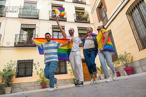 Homosexuelle männliche Freunde  die bei der Gay Pride Party vor Freude springen  Vielfalt der jungen Leute in der Stadt  Weg zur Demonstration mit den Regenbogenfahnen