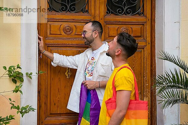 Lgbt Konzept  schwules männliches Paar schüttelt Freunde  um zur Pride Party mit Regenbogenfahne zu gehen