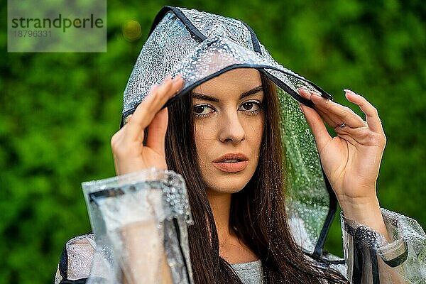 Junge schöne Frau in Regenmantel mit Kapuze an einem regnerischen Tag