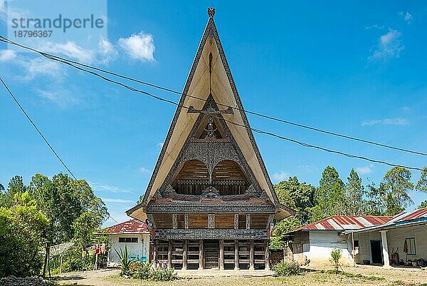 Traditionelle Batak Häuser  auf Indonesisch Rumah Bolon oder Jabu genannt  zeichnen sich durch ihre charakteristischen Dächer aus  die sich an jedem Ende nach oben wölben  wie der Rumpf eines Schiffes  und durch ihr Schnitzdekor