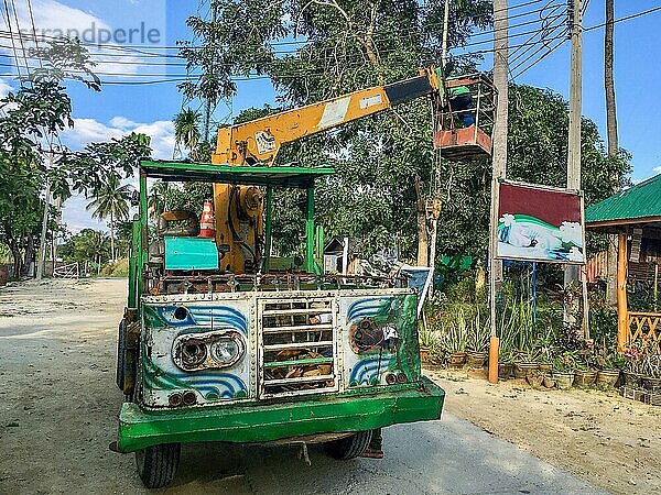 Bunter alter klassischer Hubsteiger für Wartungsarbeiten an Oberleitungen auf der Fahrbahn der Insel Ko Phayam im Süden Thailands