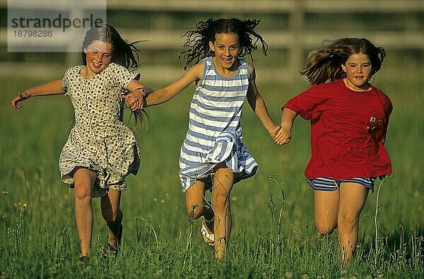 3 Mädchen beim Rennen über grüne Wiese