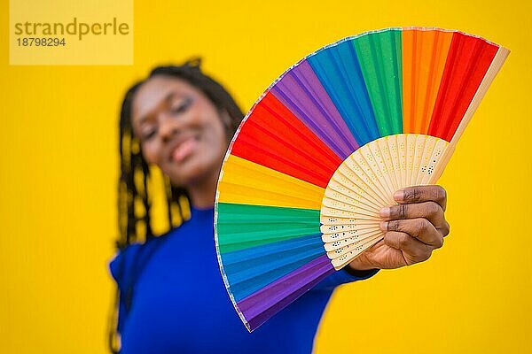 Lgbt Regenbogen Fan und eine attraktive schwarze ethnische Frau auf einem gelben Hintergrund