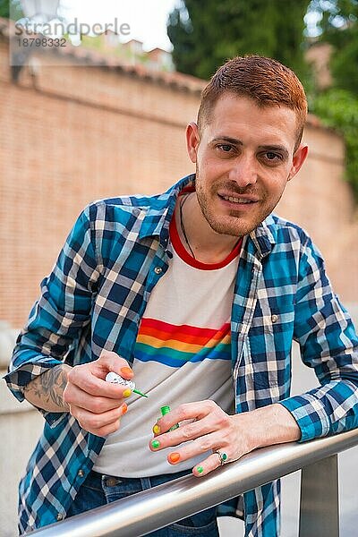 Attraktive Homosexuell Mann malt seine Nägel Make up mit Regenbogen lgbt Flagge in der Stadt  Stolz Partei und homosexuell