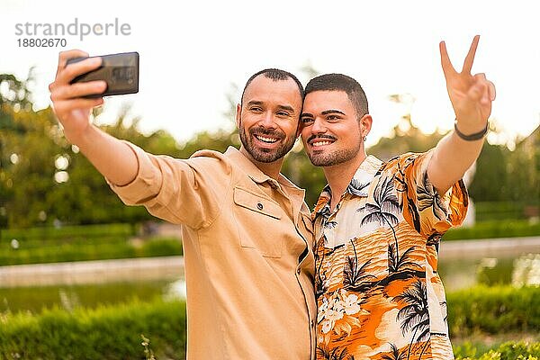 Homosexuelles Paar macht ein Selfie bei Sonnenuntergang in einem Park in der Stadt. Vielfalt und lgbt Konzept