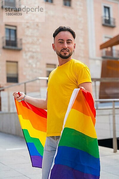 Porträt des attraktiven Homosexuell Mann lächelnd mit Regenbogen lgbt Flagge in der Stadt  Stolz und homosexuelle Partei