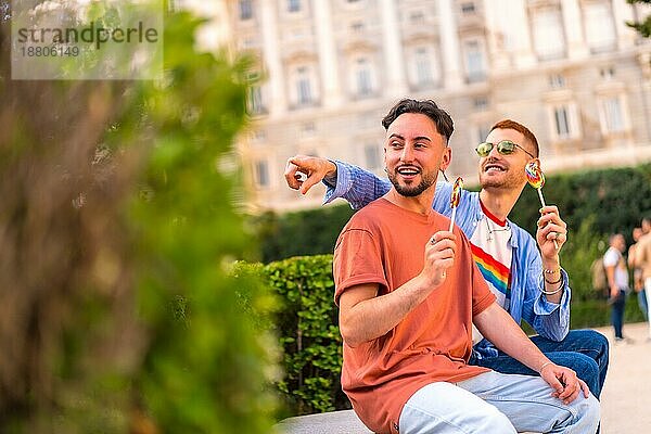 Lächelnde Hochzeit Paar essen einen Lutscher im Park auf Sonnenuntergang in der Stadt. Vielfalt und lgbt Lebensstil Konzept