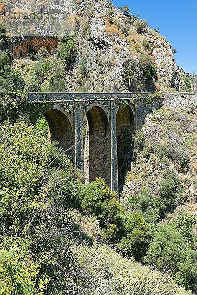 Alte Steinbogenbrücke an der alten Straße nach Rethymno. Eine Bogenbrücke ist eine Brücke mit Widerlagern an beiden Enden in Form eines gebogenen Bogens. Die Route führt durch eine wunderschöne Landschaft von Süden nach Norden