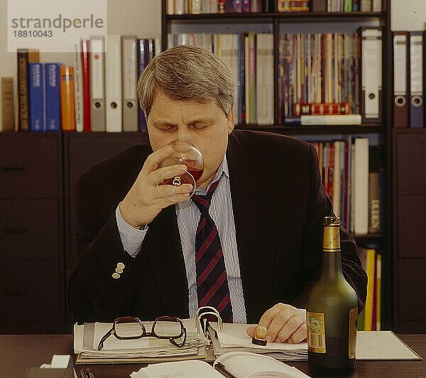 Mann trinkt Schnaps im Büro