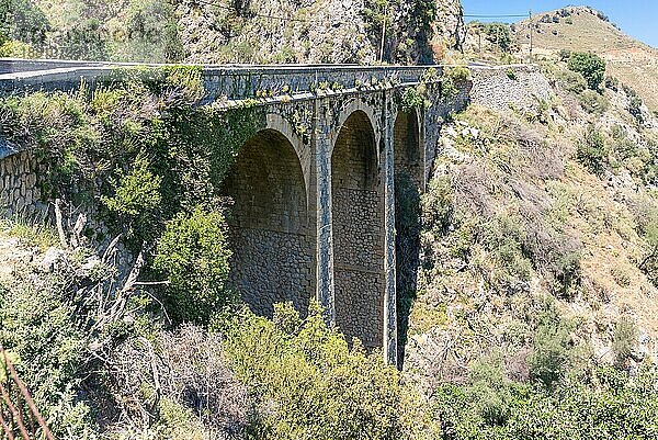 Alte Steinbogenbrücke an der alten Straße nach Rethymno. Eine Bogenbrücke ist eine Brücke mit Widerlagern an beiden Enden in Form eines gebogenen Bogens. Die Route führt durch eine wunderschöne Landschaft von Süden nach Norden