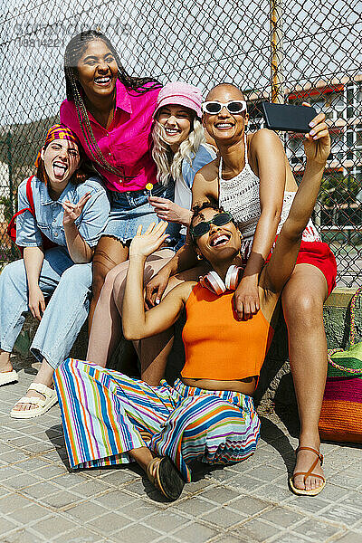Freunde machen an einem sonnigen Tag gemeinsam ein Selfie in der Nähe des Zauns