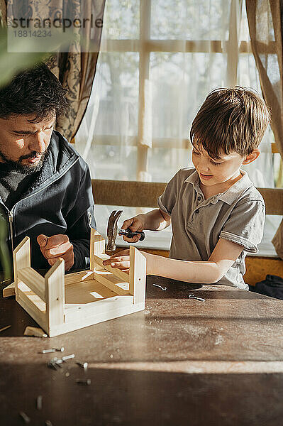 Sohn lernt  mit Vater zu Hause ein Vogelhaus zu bauen