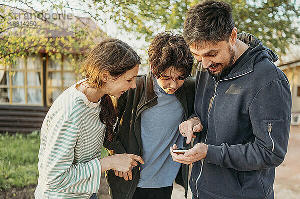 Familie teilt Smartphone vor dem Haus