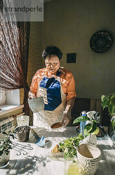 Ältere Frau hält Blumentopf und bereitet sich auf das Pflanzen vor